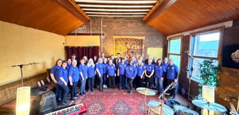 Members of the Hull NHS Choir in a rehearsal space with musical instruments