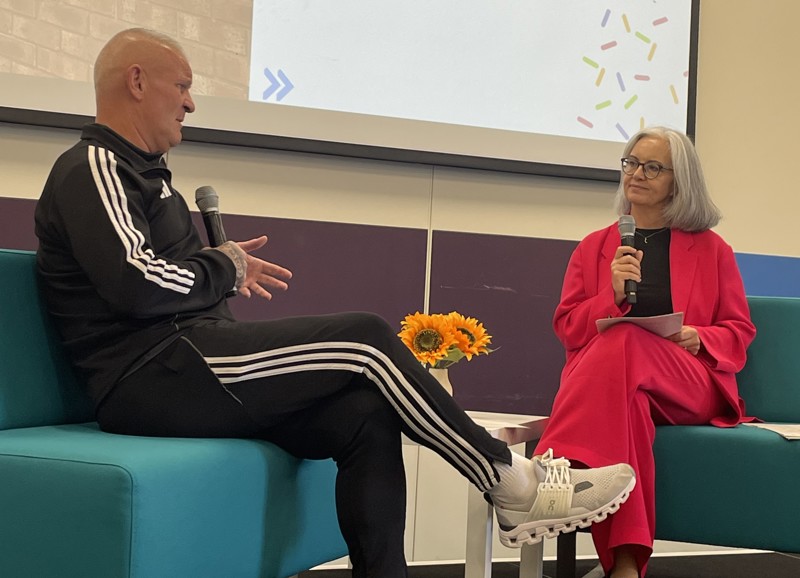 on the left dean windass talks to caroline flint, each person is sitting on a turquoise sofa and holding a microphone