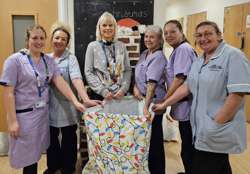 A picture of CEO Michele Moran with five Humber Trust staff members holding open a Christmas appeal bag