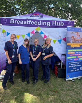 Four members of staff outside a tent designated for the Breastfeeding Hub