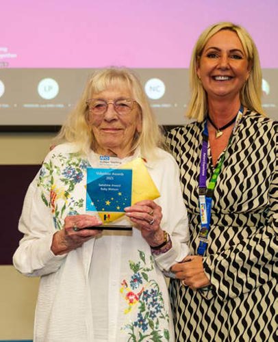 An image of a volunteer and a Trust member of staff with an award
